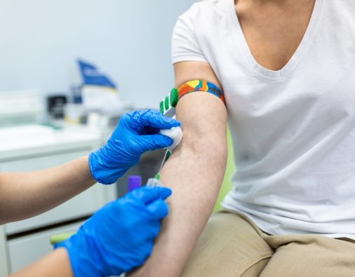 Medical technologist doing a blood draw services for patient. lab assistant with sterile rubber gloves taking blood sample from patient.